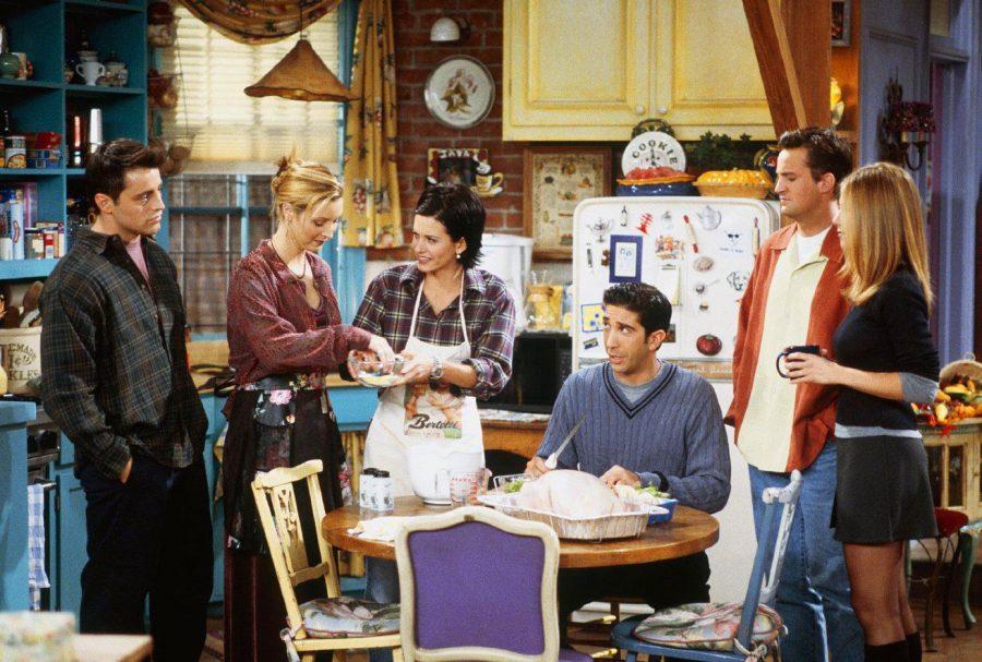The cast of Friends sitting around the Thanksgiving table in Monicas apartment.