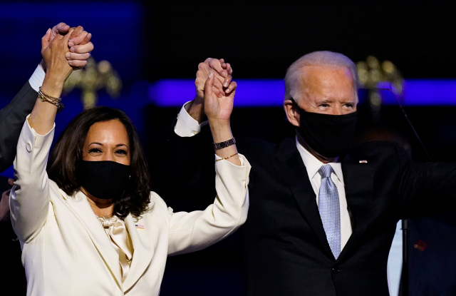 FILE - In this Nov. 7, 2020, file photo Vice President-elect Kamala Harris holds hands with President-elect Joe Biden and her husband Doug Emhoff as they celebrate in Wilmington, Del. Black policy leaders will play a pivotal role in President-elect Joe Biden’s transition team, marking one of the most diverse presidential agency review teams in history. (AP Photo/Andrew Harnik, File)